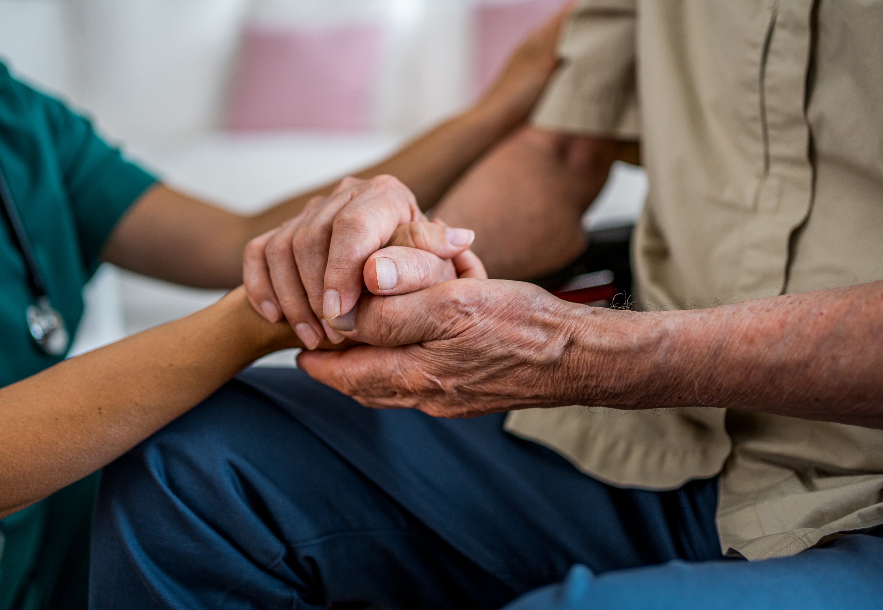 Eine Pflegekraft reicht einer älteren Person die Hand.
